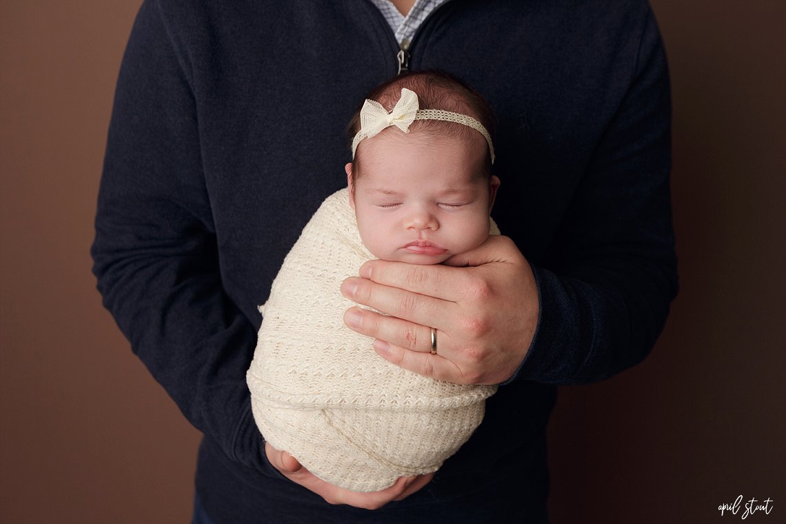 tiny baby girl swaddled in wrap held in daddy's hands glenpool photographer april stout